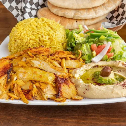 Chicken Shawarma Plate - Tender marinated chicken shawarma served with fluffy rice, fresh salad, and creamy hummus.