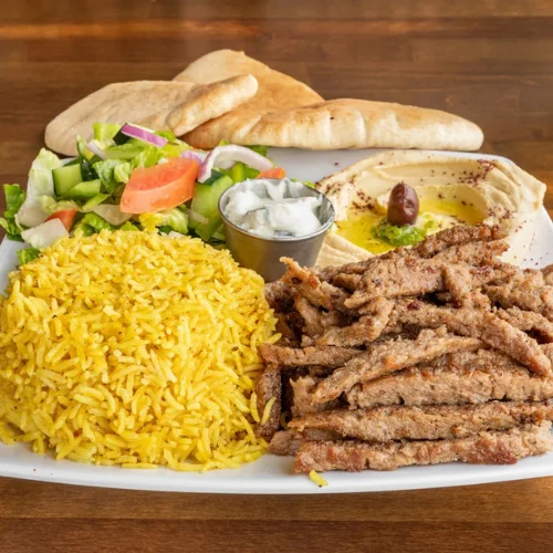 Gyro Plate - Classic gyro with seasoned lamb and beef, served with rice, salad, and our signature garlic sauce.